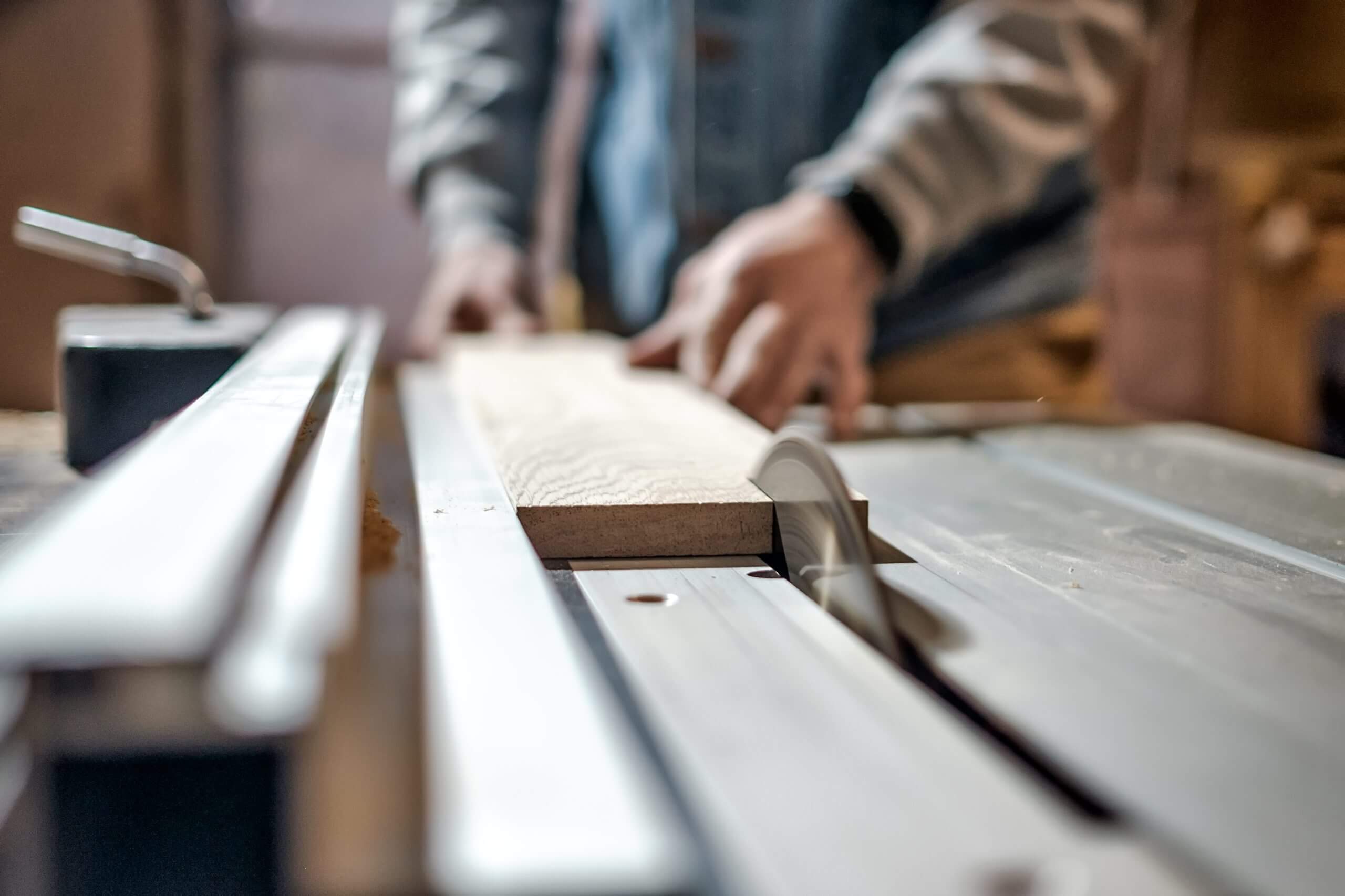 Man making wooden parts for furniture on thickness planer machine.